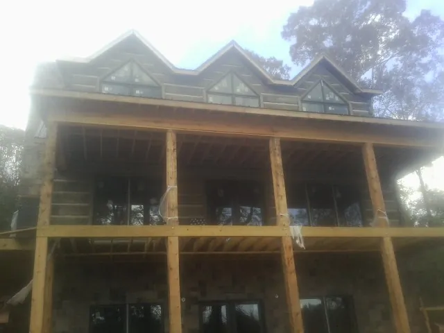 Dormers and porch framing on a large log home under construction — Roof Coating work by our crew in Harmony